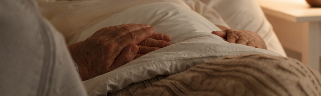 Senior people holding hands on a bed