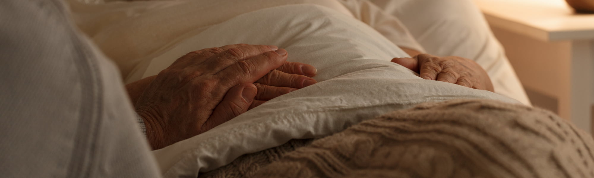 Senior people holding hands on a bed